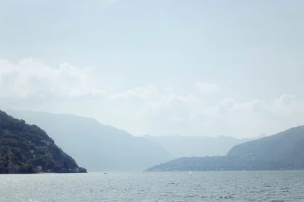 A lake and mountains in thick haze, pale and low in contrast