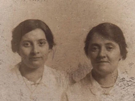 Two women in a faded sepia photo, faces soft and speckled